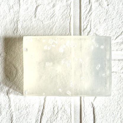 Rectangular transparent bar of soap with sea salt on a textured white background